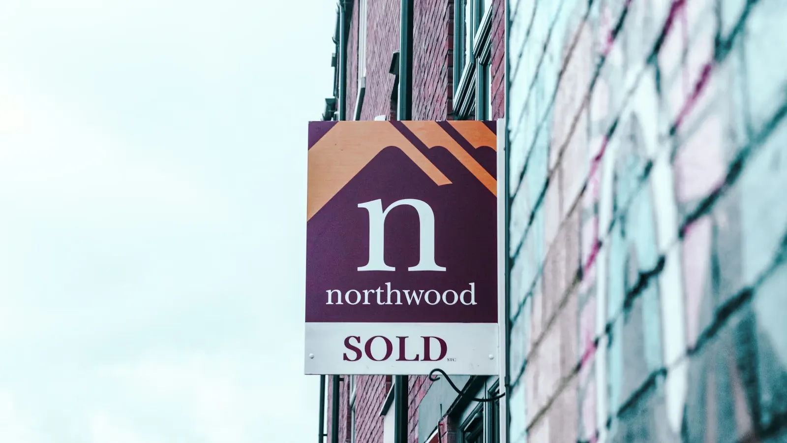 Estate agent SOLD board on a brick terraced house