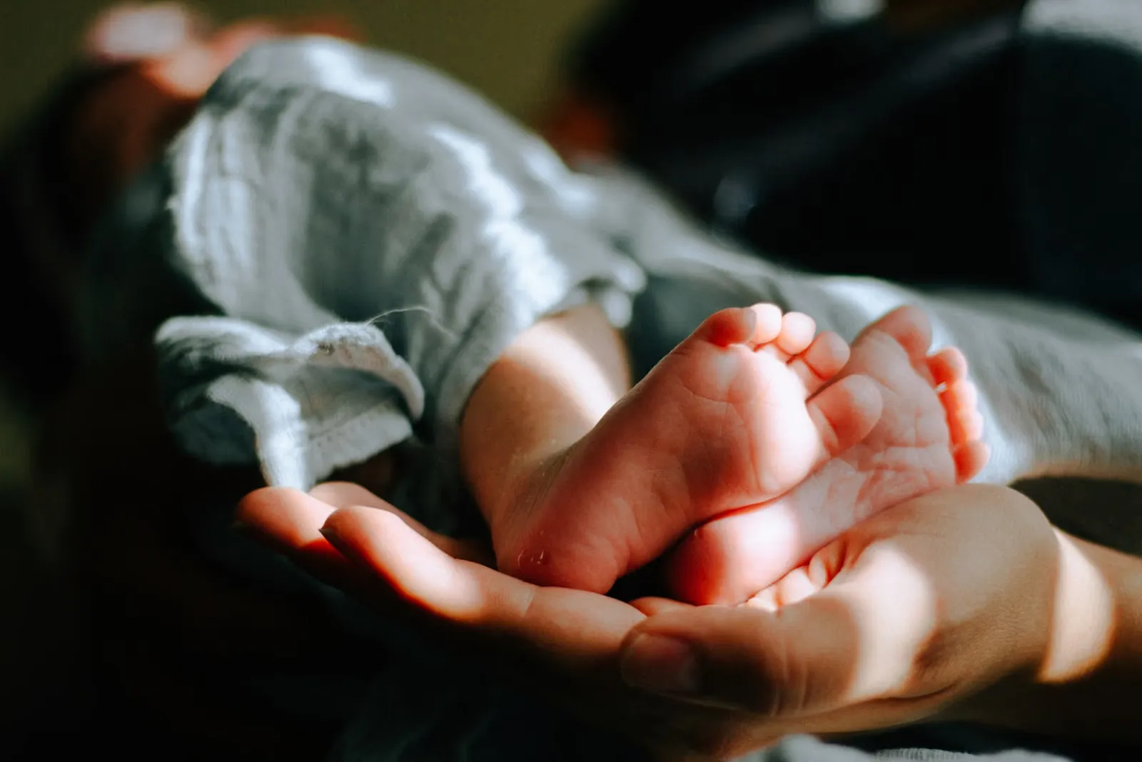 Parent cradling the feet of a newborn baby