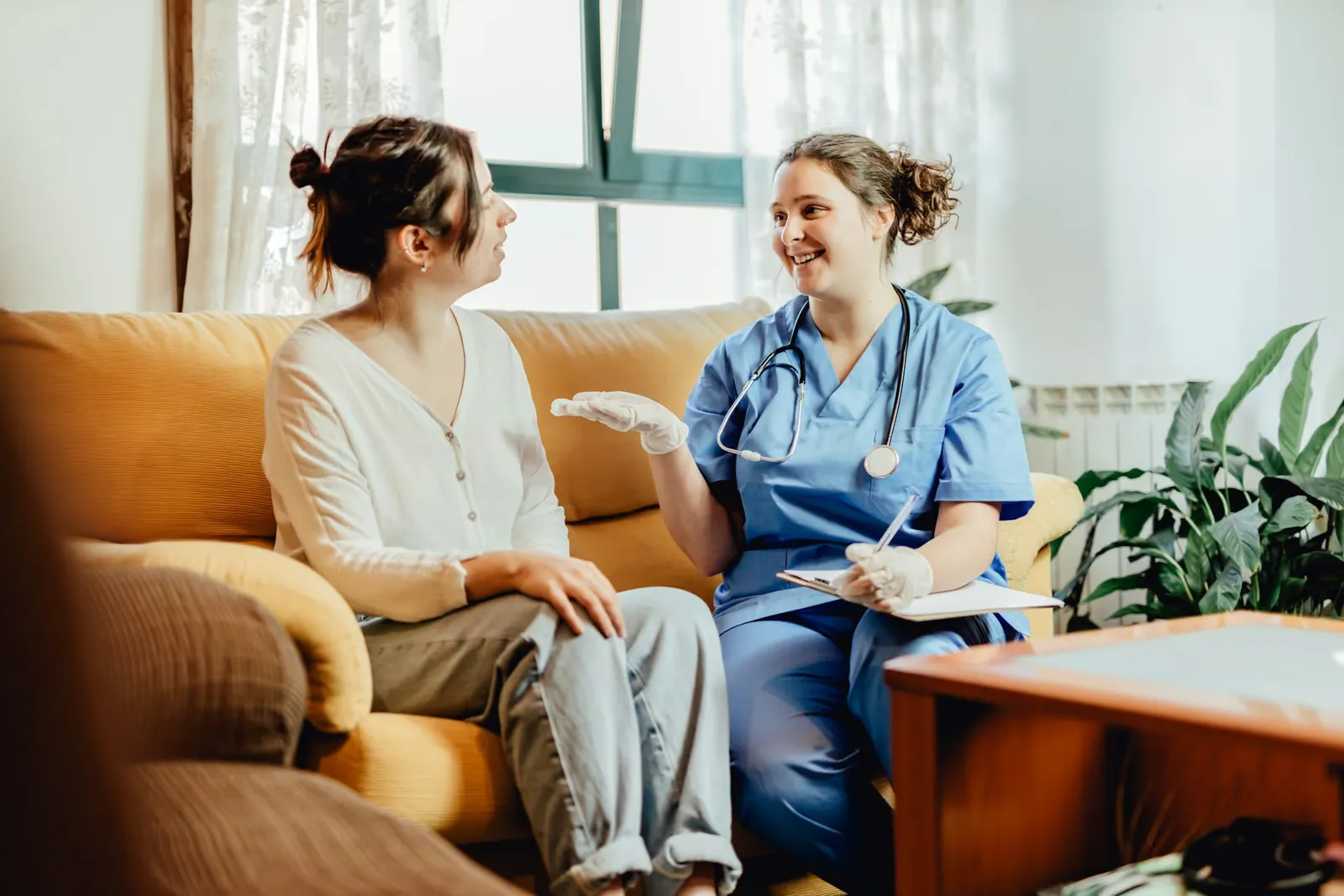 Nurse talking with a woman at home on a sofa