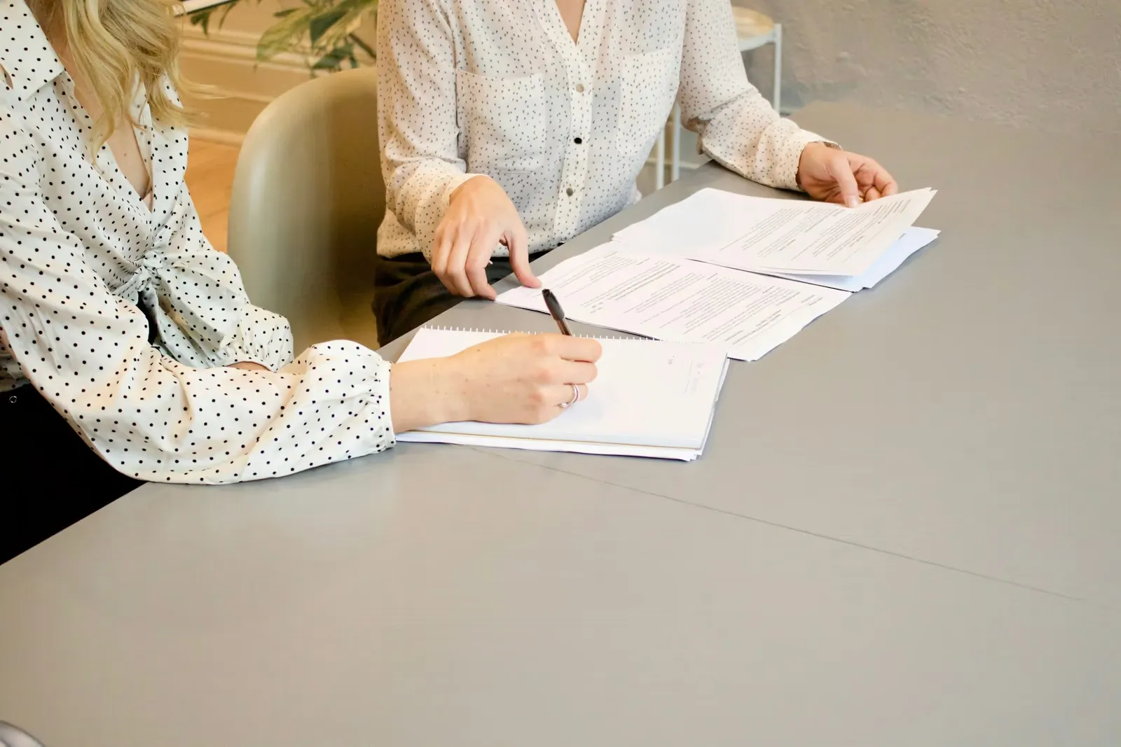 Two people reviewing mortgage paperwork and taking notes at a table