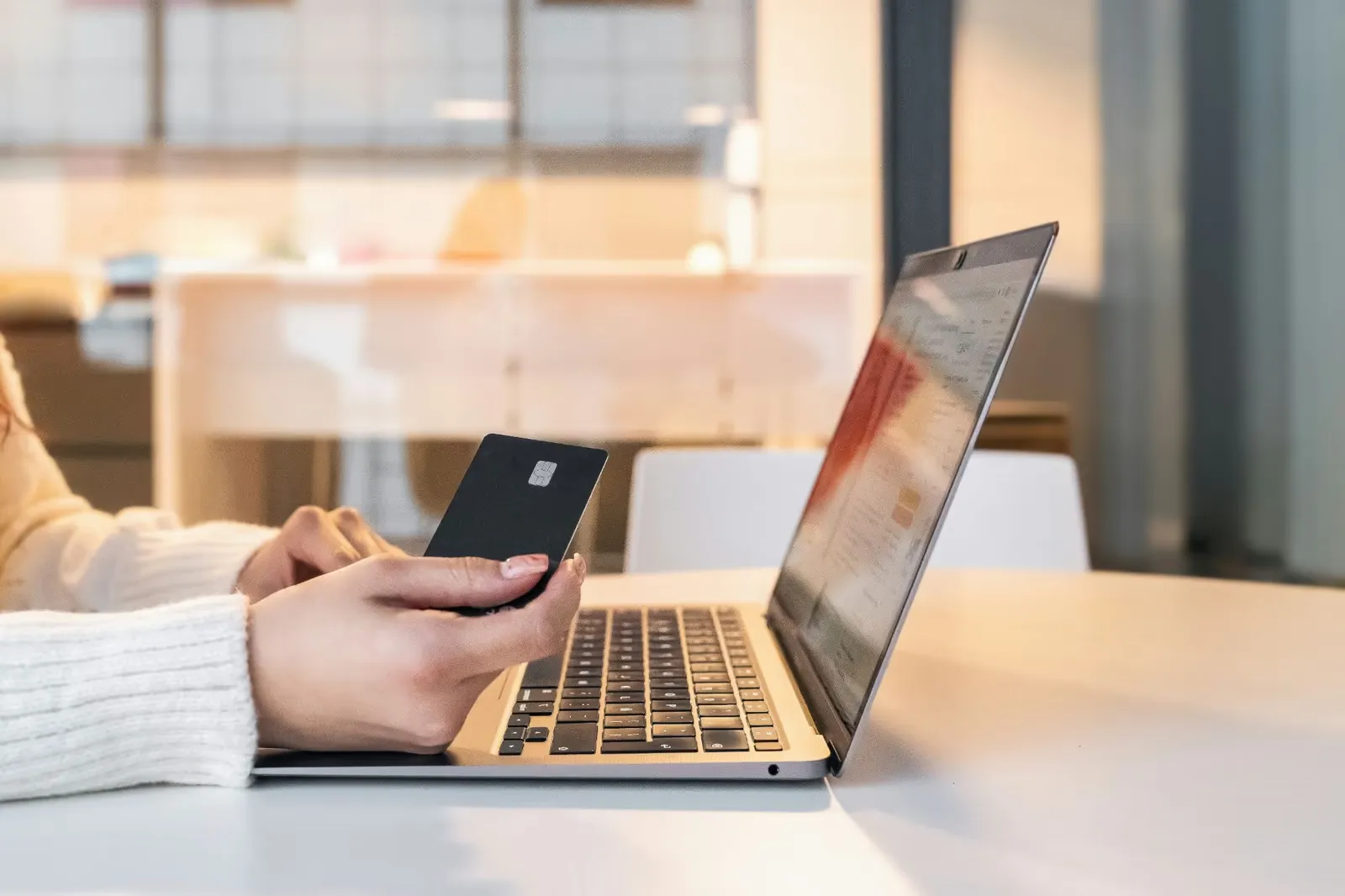 Person holding a bank card next to a laptop