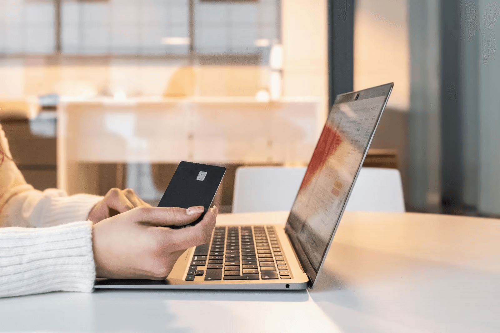 Person holding a bank card next to a laptop